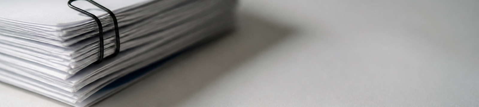 Ein Stapel weißer Blätter, zusammengehalten von einer schwarzen Büroklammer